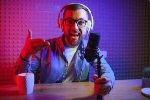 Young man recording or streaming podcast using microphone at his small broadcast studio. Content creator. photo