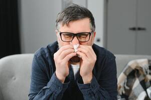 old man get a cold and sneeze with tissue paper at home photo