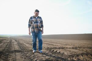 The farmer works on the ground. Male farmer on a plowed field, planting cereals in the spring in the ground. Agricultural business concept. Growing food, vegetables. photo