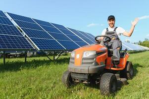 A man mows the grass near the solar panels. Green energy photo
