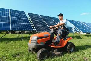 A man mows the grass near the solar panels. Green energy photo