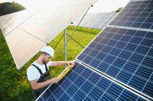 Side view of male worker installing solar modules and support structures of photovoltaic solar array. Electrician wearing safety helmet while working with solar panel. Concept of sun energy photo