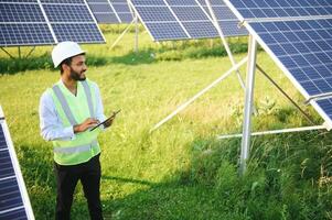 Portrait of Young indian male engineer standing near solar panels, with clear blue sky background, Renewable and clean energy. skill india, copy space. photo