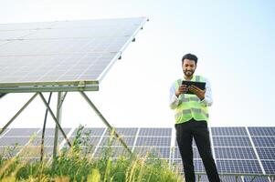 Portrait of Young indian male engineer standing near solar panels, with clear blue sky background, Renewable and clean energy. skill india, copy space. photo