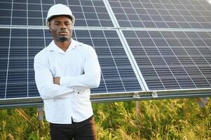 Young African American engineer in a field of solar panels. photo