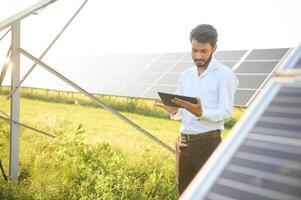 Portrait of Young indian male engineer standing near solar panels, with clear blue sky background, Renewable and clean energy. skill india, copy space. photo