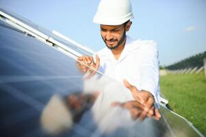Portrait of Young indian male engineer standing near solar panels, with clear blue sky background, Renewable and clean energy. skill india, copy space. photo