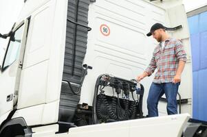 View of a driver connecting the power cables to trailer of a commercial truck. photo