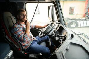 Man trucker driving in a cabin of his truck and talking on radio transmitter. photo