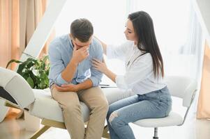 Depressed man speaking to a therapist while she is taking notes photo