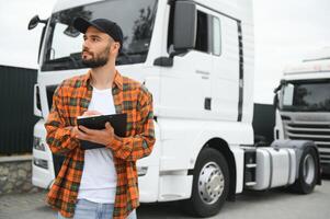 Truck driver checking shipment list while standing on parking lot of distribution warehouse photo