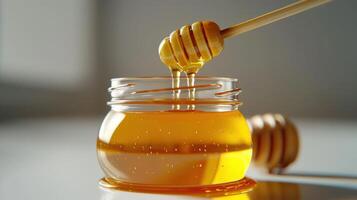 Honey Dripping From Wooden Dipper Into Clear Glass Jar on White Background. photo