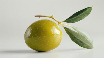 Lush Green Olive With Glossy Skin And Fresh Leaves Against Clean White Background. photo