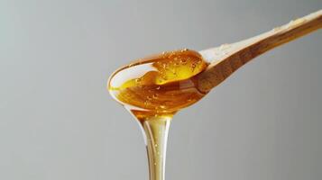 Golden Honey Dripping From Wooden Spoon on White Background During Bright Daylight. photo