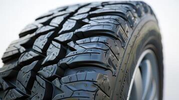 Close-Up View of All-Terrain Tire Featuring Robust Tread Design on Vehicle in Natural Setting During Daylight. photo