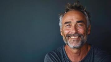 Joyful Older Man With Graying Beard Smiling in Relaxed Pose Against Dark Background photo