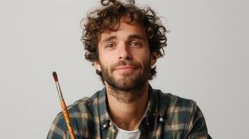 Artistic Expression of a Young Man Holding a Paintbrush in a Studio Setting During Daylight photo