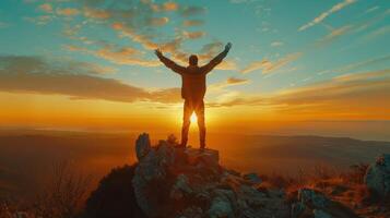 Person Standing on a Rocky Summit With Outstretched Arms Against a Stunning Sunset Over Rolling Hills photo