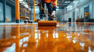 Hands-On Worker Applying Vibrant Orange Paint to Shiny Floor in Modern Warehouse During Bright Daylight Hours photo