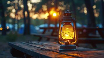 Golden Glow of a Lantern Lighting Up a Serene Campsite at Dusk Amidst Towering Trees photo