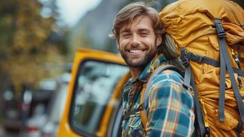 Joyful Young Hiker With Backpack Smiling Near Bright Yellow Vehicle in Autumn Wilderness photo