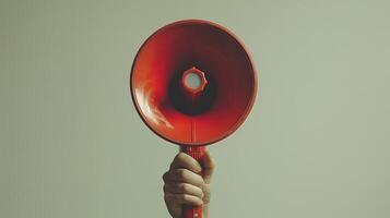 Bold Hand Holding a Vibrant Red Megaphone Against a Minimalistic Background photo