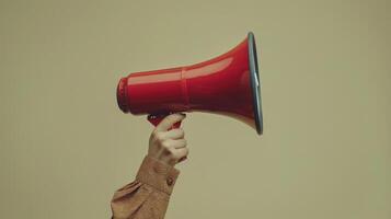 A Hand Holding a Red Megaphone Against a Soft Yellow Background During a Peaceful Advocacy Moment photo