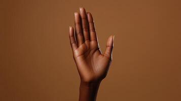 A Raised Hand Against a Solid Brown Background Signifying Communication and Expression photo