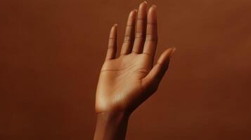 A Close-Up View of an Upward Reaching Hand Against a Warm Brown Background in Soft Natural Light photo