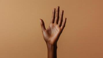 A Raised Hand Displaying Graceful Gesture Against Warm Brown Background in Modern Art Style photo