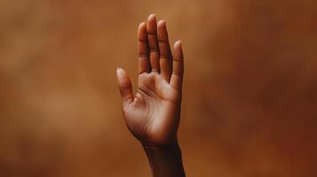 An Outstretched Hand Gesturing for Attention Against a Brown Background photo
