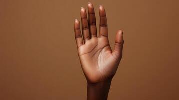 Hand Raised Against Brown Background Expressing Openness and Communication in Minimalist Setting photo