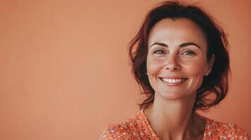 A Cheerful Woman Smiling Against a Warm Orange Background in Bright Casual Attire photo