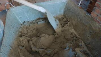 Mixing Cement for Construction Project, Close-up of cement being mixed in a large container at a construction site. The mixture appears thick and ready for use in building structures. video