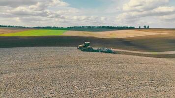 The tractor is working in the field, plowing the land. Preparing the soil for planting a new crop, agriculture concept, top view. video