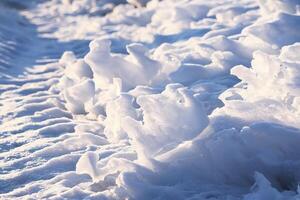 Melting snow and ice surface close up in evening sunlight in wintertime photo
