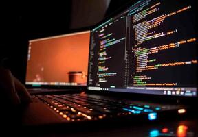 Software developer writing code on laptop keyboard at night photo