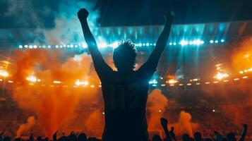 Soccer supporter raises his arms in excitement in a packed stadium at night photo