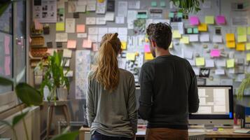 Two business people are looking at a wall covered with sticky notes in a modern office photo
