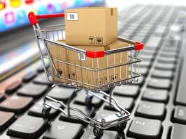 Shopping cart full of cardboard boxes standing on laptop keyboard photo