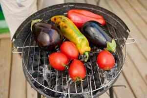 Fresh vegetables including eggplant, tomato, and peppers grilling on a barbecue photo
