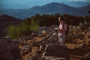 Man hiking on rocky trail with scenic mountain views and camera in hand photo