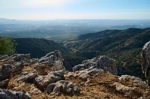 Panoramic view of lush green mountain range and farmland from rocky cliff photo