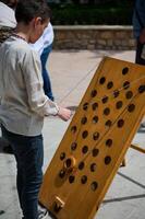 Boy playing with a wooden ring game outdoors during a sunny day photo