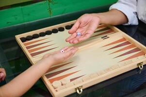 Close-up of two hands playing backgammon with dice on a wooden board game photo