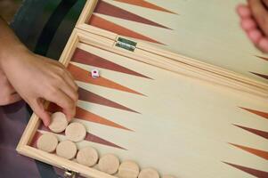 Close-up of hands playing a backgammon game with wooden pieces and a dice photo