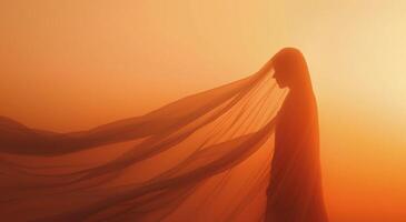 Silhouetted Figure With Flowing Veil Against Orange Sunset Sky photo