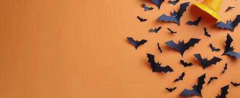 Halloween Decorations With Black Paper Bats and Yellow Hat on Orange Background photo