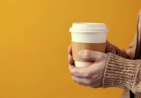 Warm Drink Held Against Yellow Background in Cozy Indoor Setting photo