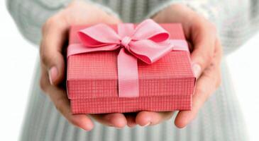 Gift Wrapped in Pink Ribbon Presented by Hands in Soft Light photo